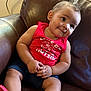 Hazen is registered to the contest to win money with this photo: toddler, child, baby, red_shirt, red_shoes, leather_couch, indoor, person, cute, smiling, sitting, shorts, skin, face, hand, arm, leg, furniture, home, expression