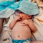 Archie joined the competition — help win amazing prizes! baby, infant, hat, blue_hat, diaper, towel, blanket, skin, hand, fingers, lying_down, relaxed, indoors, cute, child, face, ear, belly, soft_texture, resting