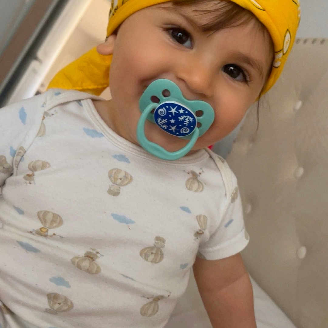 Ghaith is registered to the contest to win money with this photo: baby, bandana, bed, casual, child, clothing, cute, face, happy, headwear, indoor, infant, one_person, pacifier, person, portrait, sitting, skin, smiling, young_child
