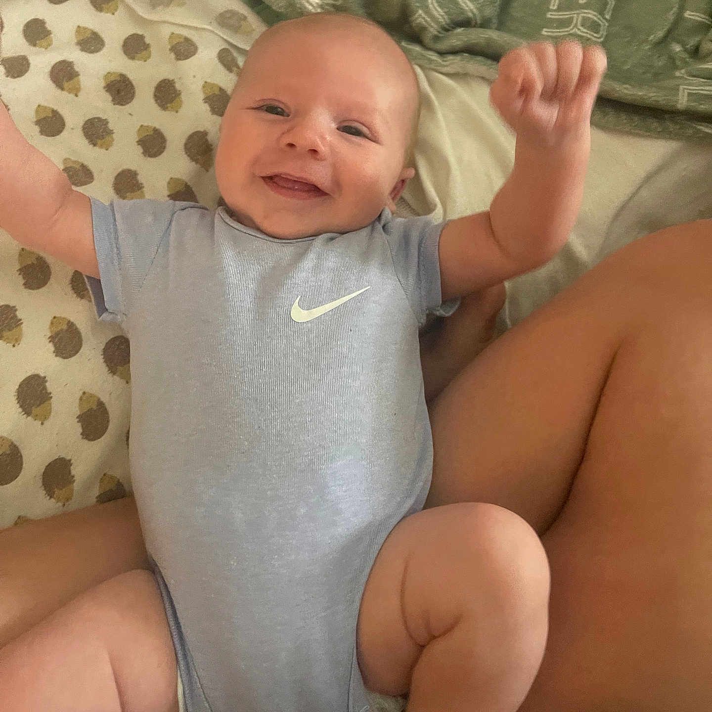Oliver joined the competition — help win amazing prizes! arms_raised, baby, blanket, blue_clothing, child, chubby_legs, comfort, cozy, cute, face, happy, indoors, infant, lying_down, newborn, onesie, person, pillow, skin, smiling