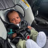 baby, car_seat, infant, hoodie, seatbelt, pacifier, clothing, car_interior, socks, green_pants, black_straps, sitting, child, serious_expression, safety, automobile, infant_care, cute, portrait, indoors