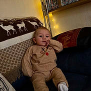 Rudy joined the competition — help win amazing prizes! baby, child, couch, blanket, knitwear, socks, indoor, homedecor, fairy_lights, dvd_collection, child_clothing, reindeer_pattern, cozy, portrait, seated, furniture, soft_lighting, warm_colors, relaxed, contemplative