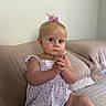 Huntleigh joined the competition — help win amazing prizes! baby, child, infant, pink_bow, sitting, couch, indoors, clothing, cute, expression, hands, face, blue_eyes, blonde_hair, pale_skin, portrait, home, soft_lighting, dress, plush