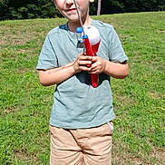 Paxston Allen is registered to the contest to win money with this photo: child, boy, fishing_pole, outdoor, grass, trees, shorts, tshirt, shoes, sunny, nature, smile, summer, recreation, greenery, playful, casual_clothing, daylight, portrait, happy
