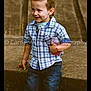 child, boy, plaid_shirt, jeans, smiling, outdoor, stone_wall, bottle, casual_clothing, short_hair, happy, portrait, young_child, holding_object, standing, nature, daylight, cute, person, kid