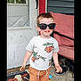 Liam Andrew joined the competition — help win amazing prizes! toddler, child, sunglasses, baby_yoda, tshirt, shorts, shoes, porch, door, doormat, cow, sunflowers, chair, cushion, concrete_floor, smiling, standing, outdoor, casual_clothing, person