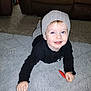 Liam Andrew joined the competition — help win amazing prizes! toddler, child, smiling, beanie, black_shirt, red_wrappers, rug, carpet, indoor, living_room, couch, happy, face, person, cute, young_child, floor, light_skin, blue_eyes, casual_clothing