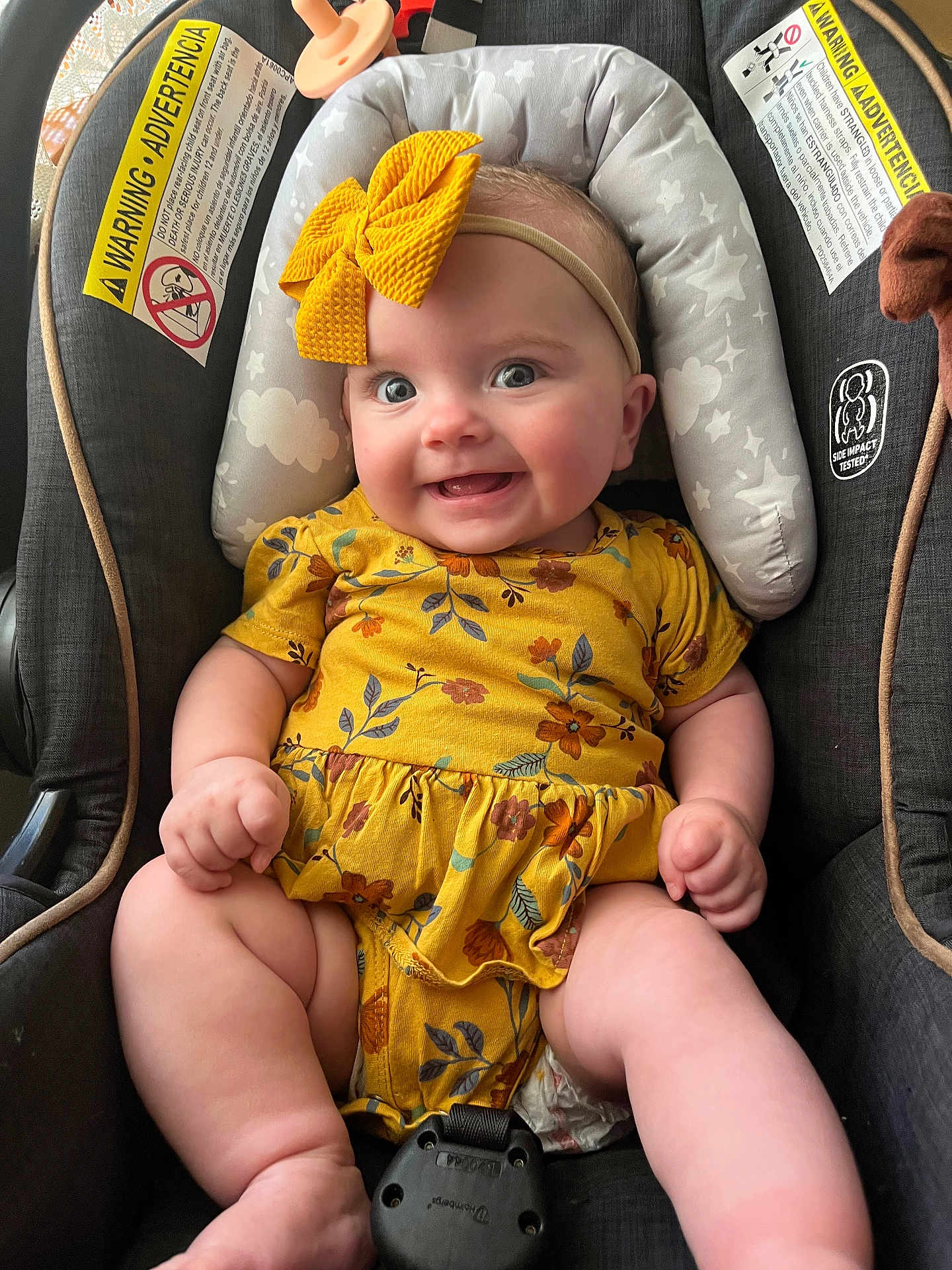 Delia joined the competition — help win amazing prizes! baby, smiling, yellow_bow, floral_outfit, car_seat, safety_warning, cushion, child, cute, infant, happy, person, seatbelt, headband, plush, indoors, skin, legs, chubby, tongue
