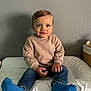Lylio participe au concours pour gagner de l'argent avec cette photo : toddler, child, smile, sitting, blue_socks, beige_sweater, jeans, indoor, face, hair, hands, changing_pad, wall, light, cozy, cute, happy, portrait, young_child, casual_clothing