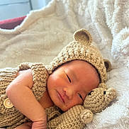Wyatt is registered to the contest to win money with this photo: baby, newborn, knitted_clothing, bear_hat, crocheted_toy, teddy_bear, blanket, soft_texture, sleepy, infant, cute, portrait, resting, cozy, hand, face, indoors, warm, comfort, child