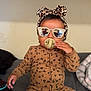 baby, child, pacifier, sunglasses, headband, leopard_print, pajamas, bed, blanket, indoor, person, cute, fashion, reflection, cozy, sitting, infant, portrait, accessory, comfort
