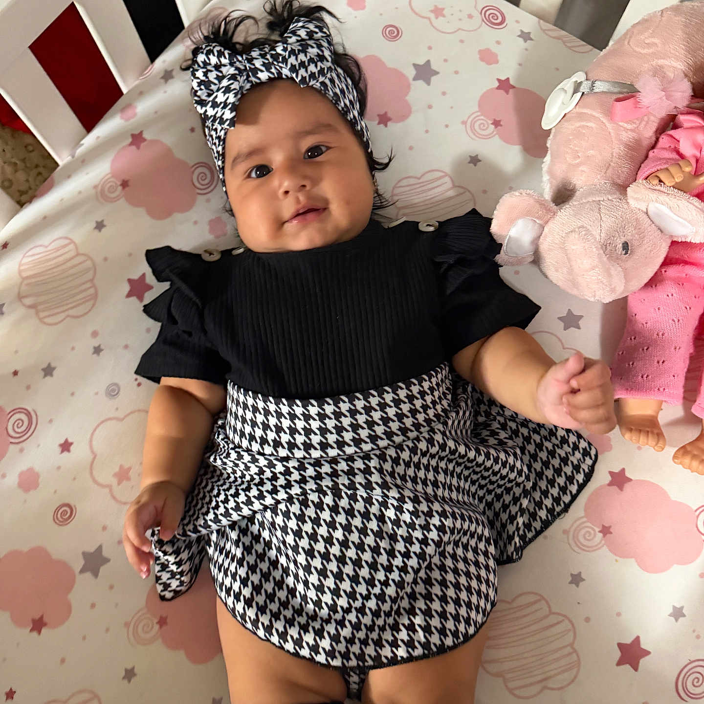 Kelsey joined the competition — help win amazing prizes! baby, child, infant, portrait, lying_down, crib, crib_mattress, headband, dress, black_and_white, patterned_clothing, socks, plush_toy, elephant, pink, stars, clouds, indoors, smiling, fashion