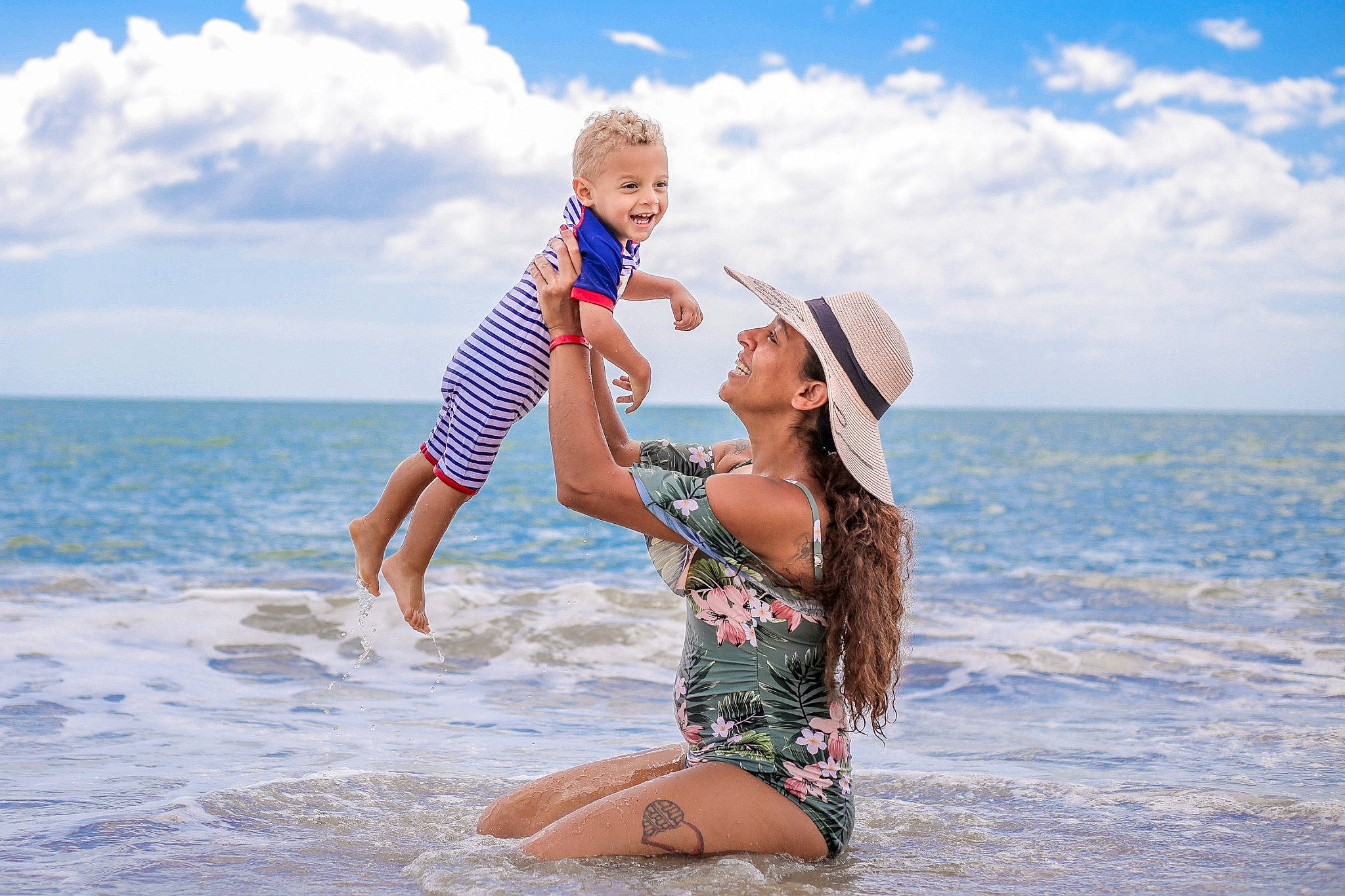 Theodore joined the competition — help win amazing prizes! azure, beach, body_of_water, cloud, flash_photography, fun, gesture, happy, hat, headwear, joy, leisure, people_in_nature, people_on_beach, person, sky, smile, summer, swimwear, toddler