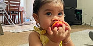 Daphne is registered to the contest to win money with this photo: toddler, child, peach, fruit, indoor, living_room, carpet, curious, baby, person, furniture, television, bracelet, hair_tie, clothing, yellow, pink, table, chair, high_chair