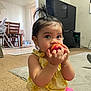 toddler, child, peach, fruit, indoor, living_room, carpet, curious, baby, person, furniture, television, bracelet, hair_tie, clothing, yellow, pink, table, chair, high_chair