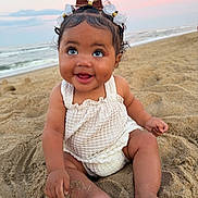 Adelina is registered to the contest to win money with this photo: baby, child, sand, beach, sunset, smile, happy, cute, bow, hair_accessory, ocean, water, sky, outdoor, summer, toddler, sitting, clothing, infant, portrait