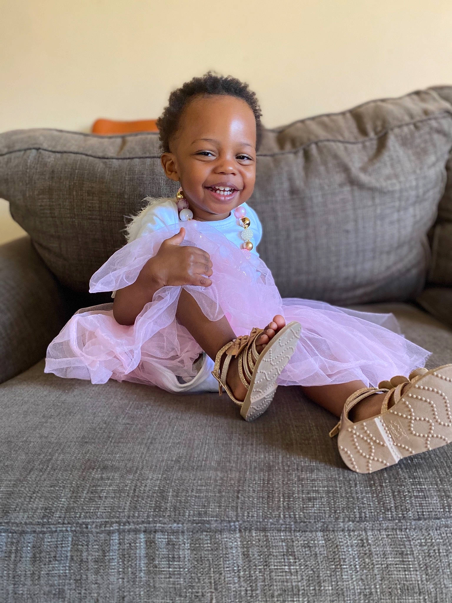 Mila is registered to the contest to win money with this photo: baby_toddler_clothing, comfort, couch, eye, finger, floor, flooring, hair, happy, head, human_leg, joint, joy, knee, leg, person, skin, sleeve, smile, thigh