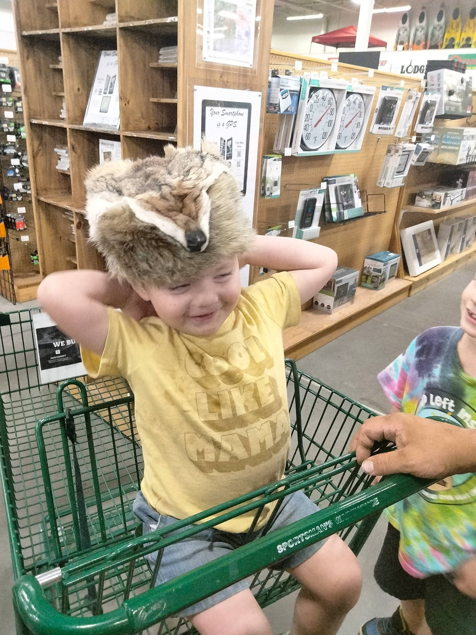 Oliver is registered to the contest to win money with this photo: bookcase, cart, chair, child, engineering, event, fun, joy, leisure, person, photograph, publication, retail, room, shelf, shelving, shopping_cart, shorts, sitting, smile
