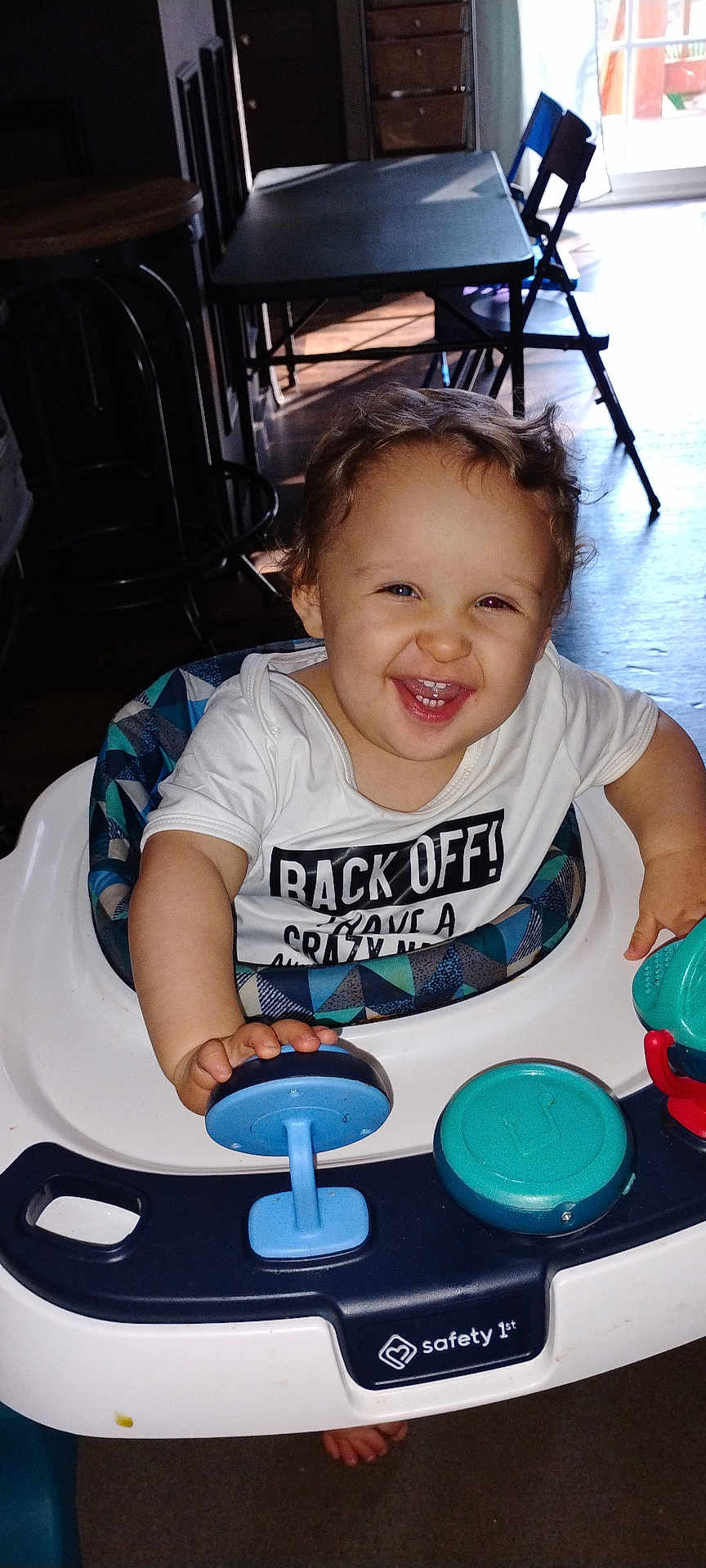 Sylas is registered to the contest to win money with this photo: toddler, baby_walker, child, smiling, indoor, toy, play, happy, person, clothing, face, hand, furniture, sunlight, floor, foot, seat, plastic, pattern, curtain