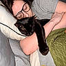 person, cat, sleeping, glasses, black_cat, bed, pillow, blanket, arm, indoor, resting, cozy, cute, pet, animal, nap, comfort, human, stretching, quilting