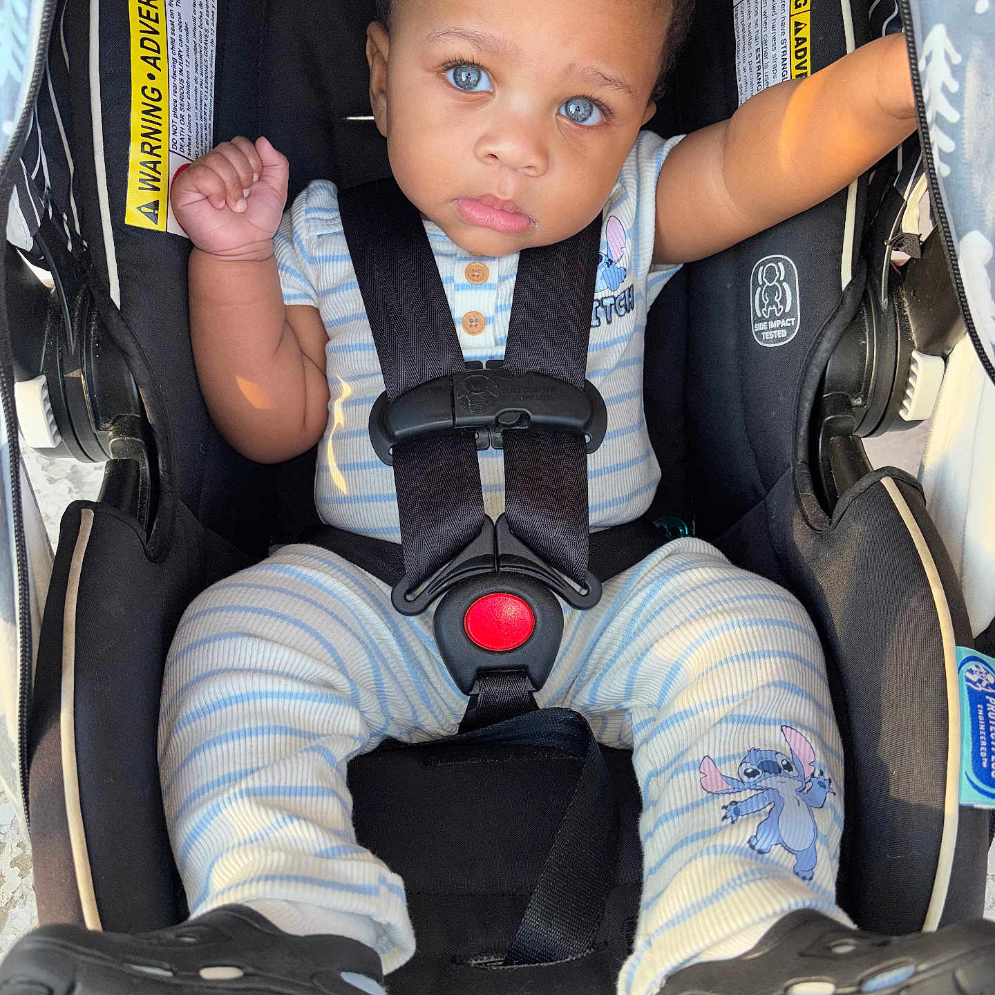 Drayden is registered to the contest to win money with this photo: baby, child, car_seat, blue_eyes, onesie, striped_clothing, stitch_character, footwear, black_shoes, seatbelt, infant, cute, drool, curious, indoor, close_up, baby_clothing, safety_harness, person, portrait