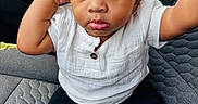Drayden is registered to the contest to win money with this photo: toddler, child, car_seat, white_shirt, black_pants, sneakers, blue_eyes, curly_hair, seated, car_interior, portrait, cute, looking_at_camera, casual_clothing, baby, young_child, indoor, car, seatbelt, person