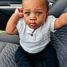 toddler, child, car_seat, white_shirt, black_pants, sneakers, blue_eyes, curly_hair, seated, car_interior, portrait, cute, looking_at_camera, casual_clothing, baby, young_child, indoor, car, seatbelt, person