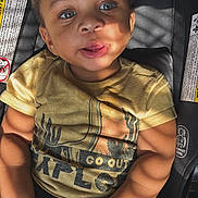 Drayden is registered to the contest to win money with this photo: baby, car_seat, casual, child, clothing, cute, expression, eyes, face, hands, indoor, infant, portrait, seatbelt, shadows, skin, sunlight, toddler, yellow_tshirt, young