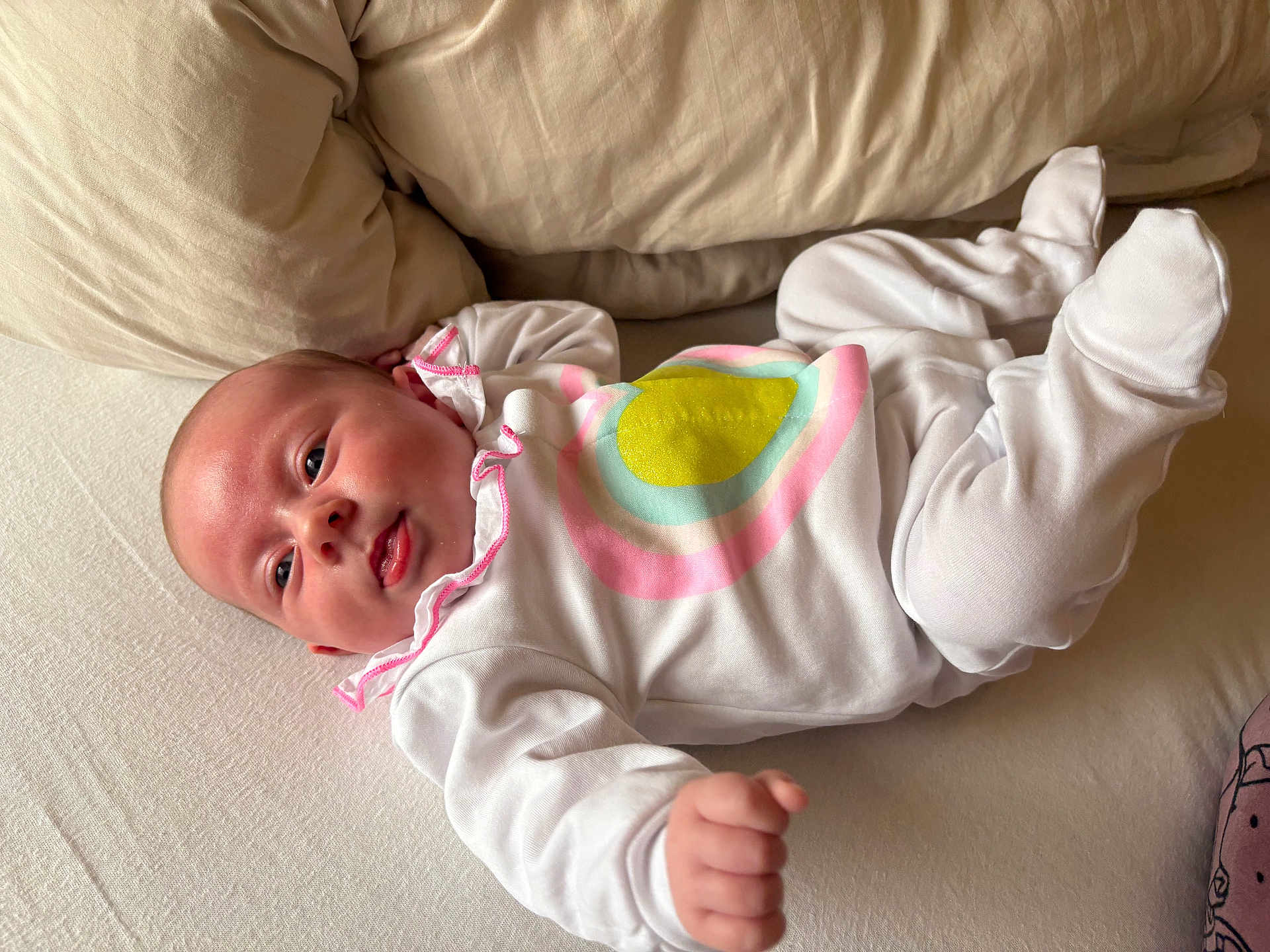 Aimée a rejoint le concours — aidez-le/la à gagner de superbes lots ! baby, infant, bed, pillow, white_clothing, colorful_pattern, face, hand, footed_pajamas, sleepwear, lying_down, indoors, skin, head, cute, newborn, person, portrait, expression, child
