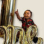 Jaxon joined the competition — help win amazing prizes! balloon, black_shorts, black_socks, celebration, child, curly_hair, cute, expression, floral_shirt, gold_balloon, happy, indoor, isolated_background, letter_balloon, party, person, pointing, portrait, smiling, toddler