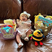 Olivia joined the competition — help win amazing prizes! baby, infant, smile, dress, headband, bow, toy, plush, bee, basket, book, couch, leather, child, cute, indoors, happy, sitting, playful, colorful