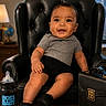baby, child, chair, leather_chair, briefcase, bottle, nameplate, smiling, indoors, window, cityscape, business, office, cute, portrait, person, black_clothing, gray_shirt, desk, happy