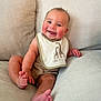 baby, smiling, bib, giraffe, couch, infant, child, happy, sitting, clothing, cheeks, face, foot, hand, indoors, cute, portrait, skin, person, comfortable