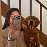 Aya participe au concours pour gagner de l'argent avec cette photo : woman, dog, golden_retriever, puppy, mirror_selfie, smartphone, jeans, watch, bracelet, wooden_stairs, hand, long_hair, indoor, casual_clothing, pet, holding, reflection, brown_dog, young_adult, portrait