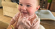 Miley joined the competition — help win amazing prizes! animal_print, baby, baby_car_seat, child, couch, cute, floor_tiles, furniture, green_wall, hand, happy, indoor, infant, living_room, person, pink_onesie, portrait, seated, smiling, television