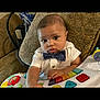 Dawson is registered to the contest to win money with this photo: baby, child, bow_tie, white_shirt, toy, colorful, piano_toy, cushion, patterned_fabric, indoor, furniture, person, infant, closeup, face, hands, seated, expression, cute, play
