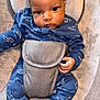 baby, infant, blue_onesie, dinosaur_pattern, seat, straps, face, eyes, hand, clothing, cute, child, indoors, portrait, newborn, sitting, fabric, soft, baby_gear, comfort