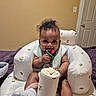 Ariyana is registered to the contest to win money with this photo: baby, child, curly_hair, cushioned_seat, cute, door, footwear, happy, indoor, infant, pacifier, patterned_seat, person, room, sitting, smiling, socks, toy, wall, white_seat
