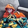 baby, blanket, child, colorful_blanket, couch, cozy, cute, expression, face, home, hoodie, indoor, infant, orange_clothing, pacifier, plush_pillow, pumpkin, sitting, sofa, warm