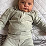 baby, infant, child, face, blue_eyes, clothing, knitwear, pillow, bed, striped_bedding, quilted_pillow, indoor, lying_down, portrait, person, cute, calm, soft_texture, comfortable, home