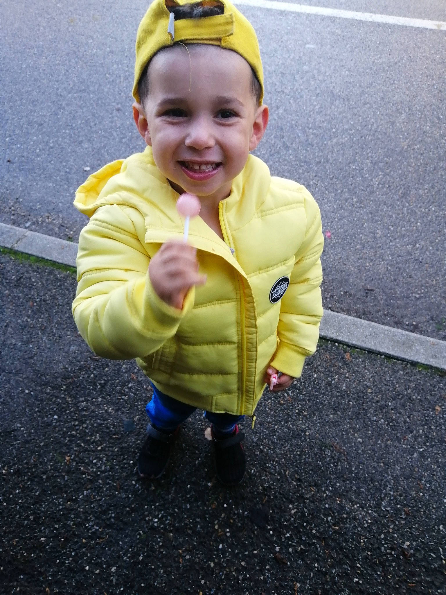 Abdallah a rejoint le concours — aidez-le/la à gagner de superbes lots ! asphalt, baby, cheek, child, cool, face, fun, head, jacket, joy, outerwear, person, personal_protective_equipment, plant, play, skin, smile, standing, toddler, yellow