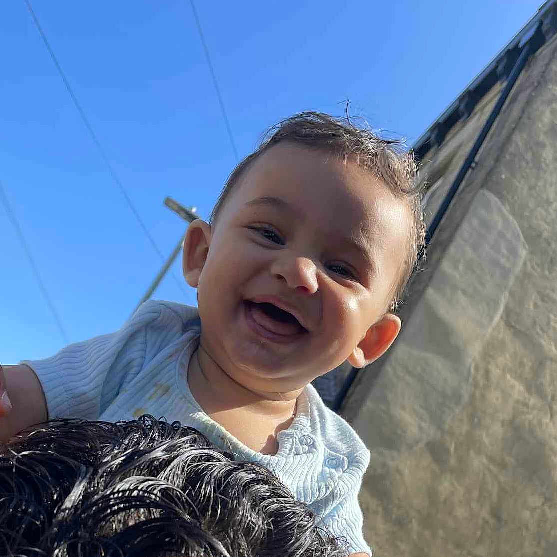 Raymon joined the competition — help win amazing prizes! baby, blue_sky, child, clothing, curly_hair, cute, face, hair, happy, head, holding, infant, joy, light, outdoor, person, playful, portrait, smiling, sunlight