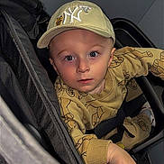 Kayden participe au concours pour gagner de l'argent avec cette photo : toddler, child, stroller, cap, beige_clothing, blue_eyes, face, hand, curious, person, infant, patterned_outfit, seated, indoor, portrait, young_child, baby, casual_wear, headwear, looking_up