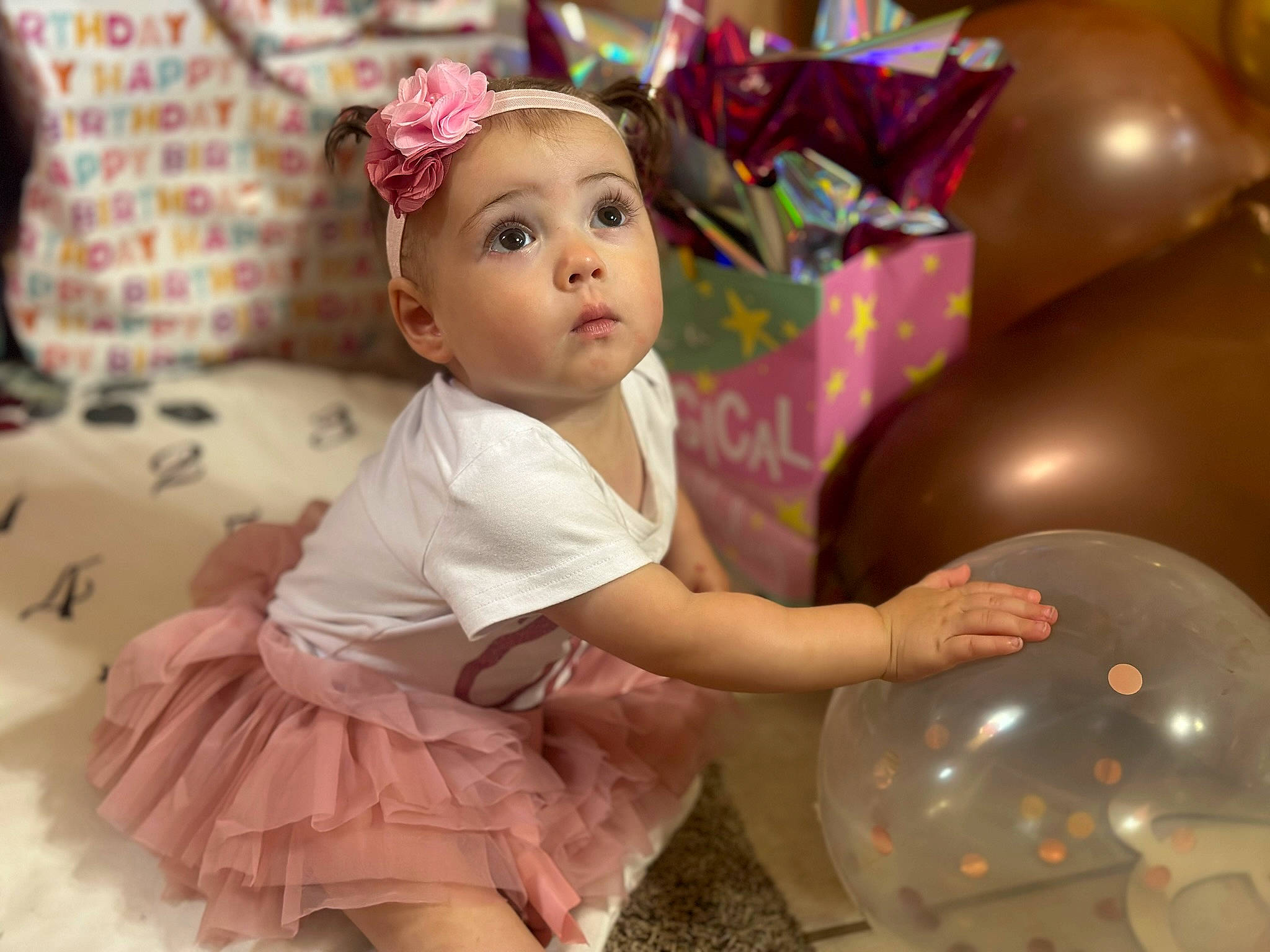 Lilly is registered to the contest to win money with this photo: baby, baby_toddler_clothing, balloon, child, dress, event, facial_expression, fashion_accessory, fun, hair_accessory, happy, headband, headpiece, headwear, magenta, party_supply, person, pink, recreation, sitting