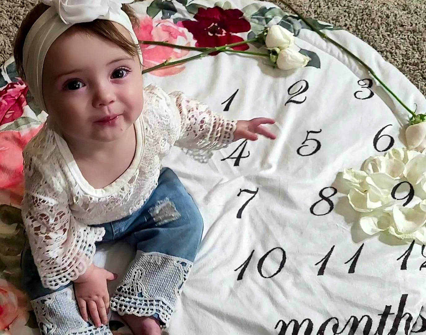 Lilly joined the competition — help win amazing prizes! baby, baby_toddler_clothing, cap, child, event, fashion_accessory, happy, linens, magenta, outerwear, pattern, person, petal, pink, product, sitting, sleeve, t_shirt, textile, toddler