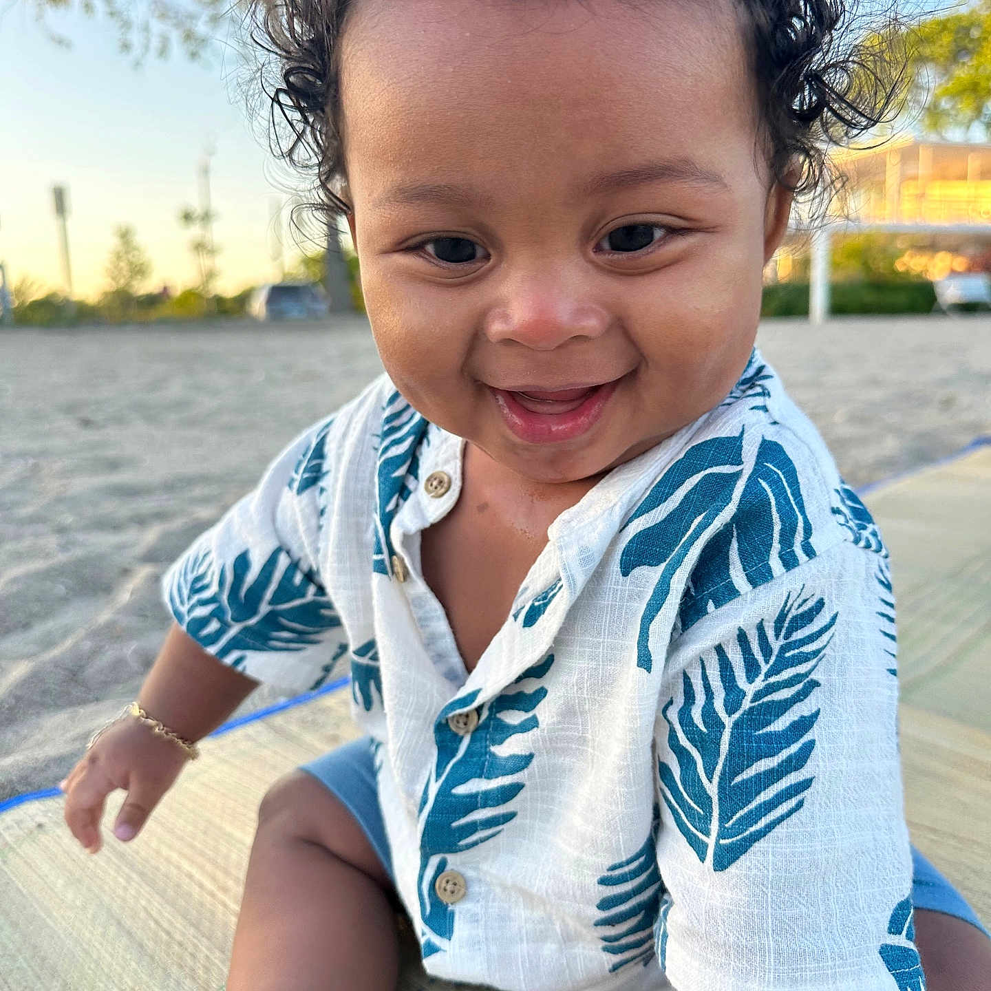 Cyaire is registered to the contest to win money with this photo: baby, child, curly_hair, daylight, foot, grass, hand, happy, leaf_pattern, mat, nature, outdoor, people, portrait, sand, shirt, sitting, smiling, sunlight, toddler