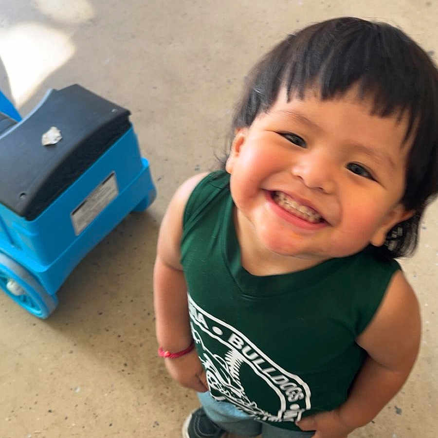 Elso joined the competition — help win amazing prizes! bracelet, casual_clothing, child, cute, floor, footwear, green_shirt, happy, indoor, looking_up, person, plastic_stool, playful, portrait, short_hair, smiling, sneakers, standing, toddler, toy