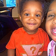 Kay'Den joined the competition — help win amazing prizes! toddler, child, indoor, orange_shirt, smiling, happy, face, person, wood_paneling, window, porch, carpet, furniture, curious, playful, sibling, family, young_child, casual_clothing, home