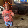 toddler, child, happy, smiling, indoors, carpet, barefoot, clothing, television, furniture, cabinet, hair_beads, orange, shorts, shirt, motion_blur, shoes, living_room, person, entertainment
