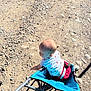Renesmee is registered to the contest to win money with this photo: baby, stroller, outdoor, dirt_path, rocks, sunlight, shadow, child, exploring, curious, clothing, red_shorts, white_shirt, baby_boy, seat, wheels, summer, daylight, head, person